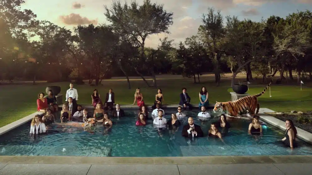 A big group of people and one tiger in a pool in a middle of a golf course.