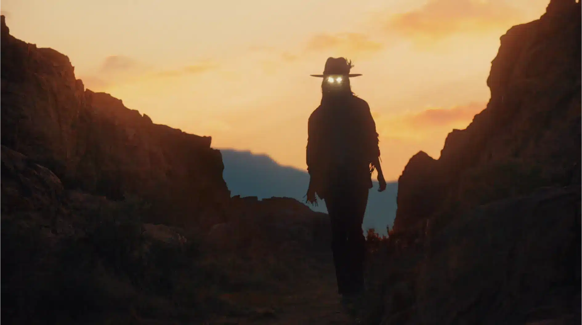 Woman with glowing eyes walking through a desert.