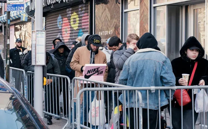 People waiting in a queue on a city street.