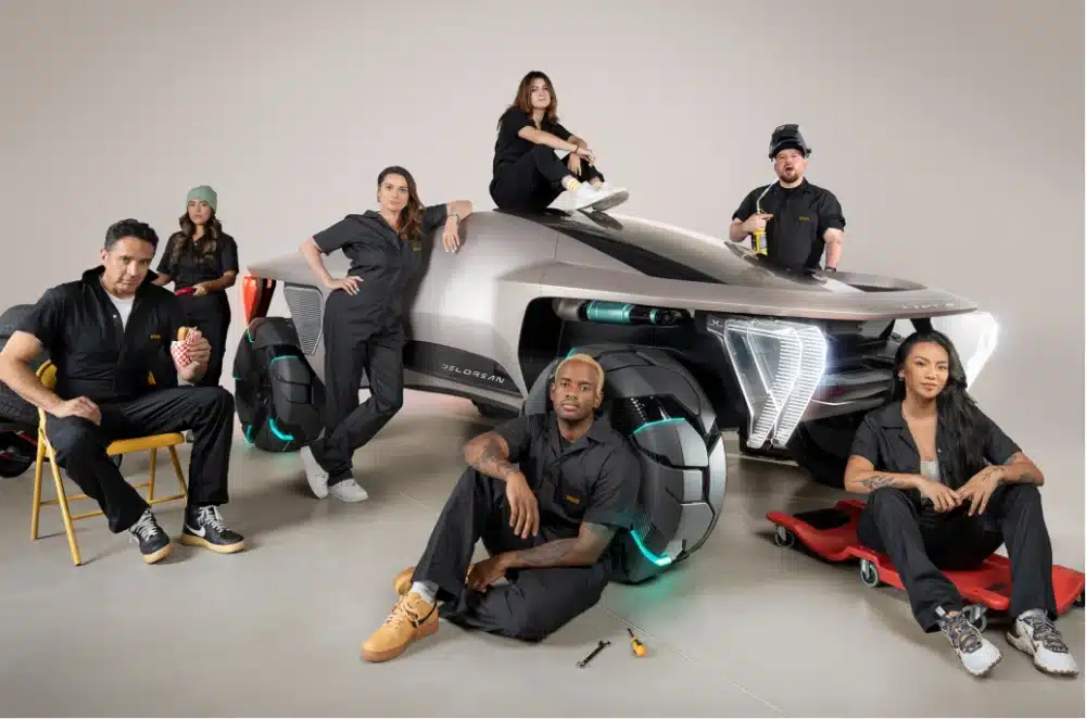 Seven people in car mechanic suits posing around a futuristic car.